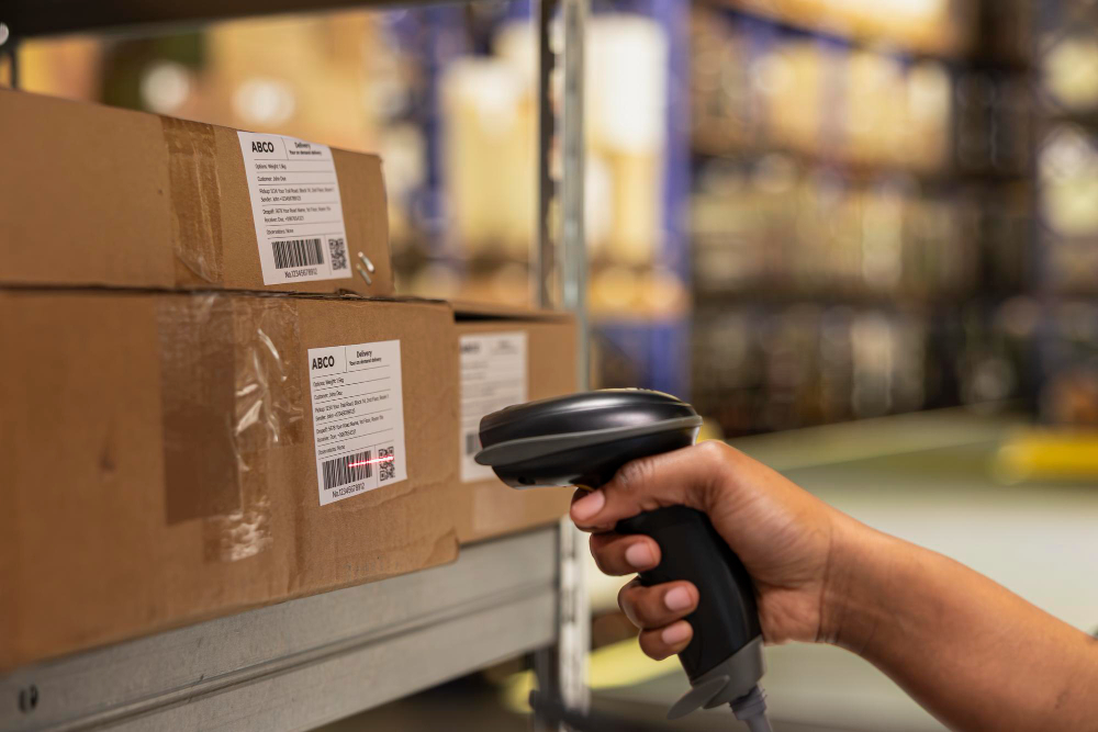 Hand scanning barcode labels on cardboard boxes in a warehouse.